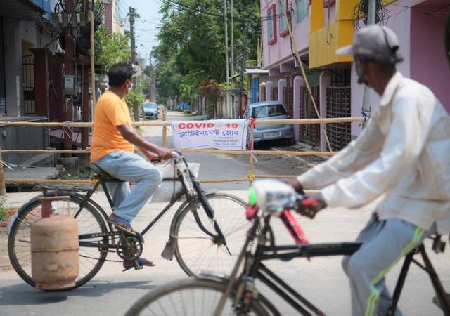 人们骑车经过印度阿加尔塔拉一处隔离区。新华社资料图