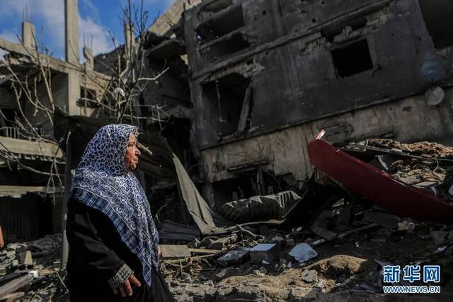 5月14日，一名女子在加沙地带拜特哈嫩查看以军空袭后的建筑。图源：新华社