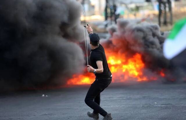 5月17日，巴勒斯坦抗议者向以色列士兵投掷石块。图源：新华社