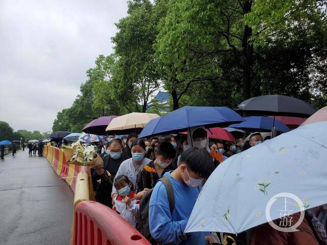 ▲23日上午，不少市民手捧鲜花举着雨伞，排起数百米长队悼念袁隆平。摄影/上游新闻记者肖鹏