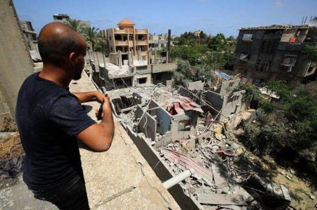 （图说：加沙地带汉·尤尼斯地区，一位男子在查看被炸毁的房屋。图/Reuters）