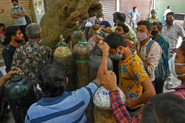 5月4日，新德里居民携氧气钢瓶排队，等待为居家隔离的新冠患者充医用氧气。（法新社）