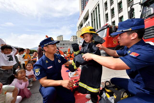 5月27日，湖北省襄阳市保康县消防救援大队队员帮助学生试穿消防灭火防护服。图自澎湃影像