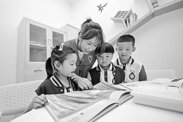 浙江湖州长兴县某儿童之家阅读驿站内，志愿者为孩子们讲解儿童绘本。新华社发