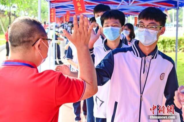 6月7日，广东省广州市南沙一中考点，老师与考生击掌为考生加油。中新社记者陈骥旻摄