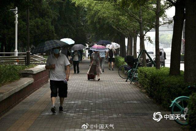 北京雷声隆隆雨水洒落 街头行人步履匆匆