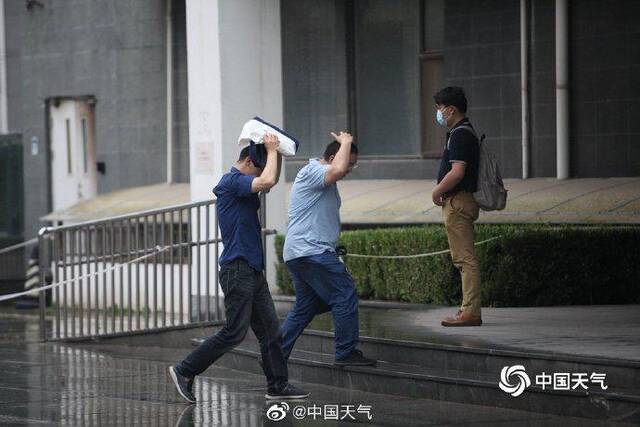 北京雷声隆隆雨水洒落 街头行人步履匆匆