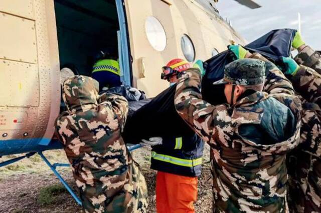  2021年5月23日，救援人员将黄河石林百公里越野赛遇难者遗体搬上转运直升机。图/新华