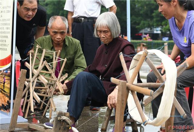 仫佬族老人正在展示仫佬族传统纺纱工艺。（蒙增师/摄）