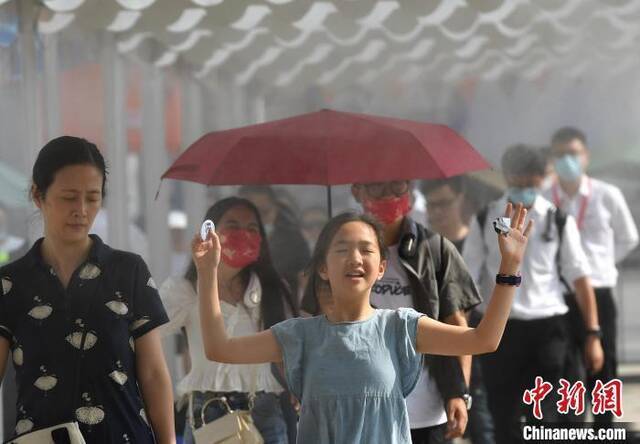 资料图：6月12日，重庆气温创新高室外最高温超35℃，图为一小朋友经过广场上的水雾降温区域。陈超摄