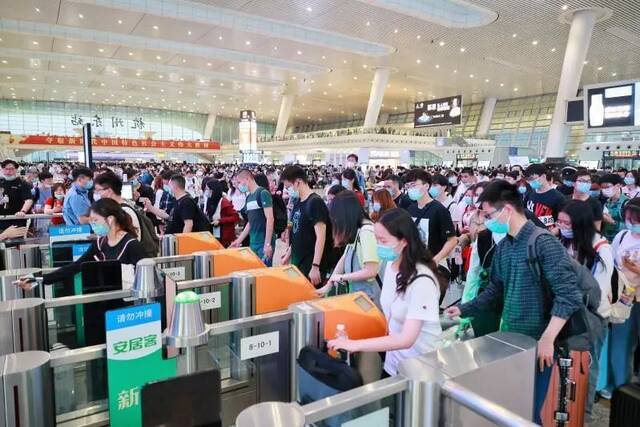 杭州东站旅客在有序通过闸机验票进站。周围摄