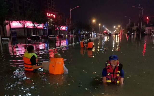 ▲濮阳市红十字救援队队员带被困市民走出积水区域。受访者供图