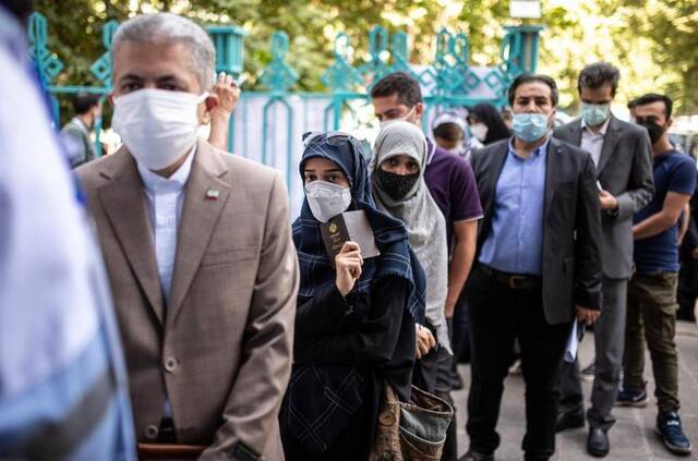 6月18日，人们在伊朗德黑兰一个投票点排队等待投票。新华社发（艾哈迈德·哈拉比萨斯摄）