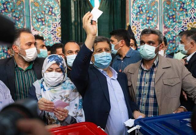 6月18日，总统候选人央行前行长阿卜杜勒纳赛尔·赫马提（中）在伊朗德黑兰一个投票点投票。新华社发（艾哈迈德·哈拉比萨斯摄）