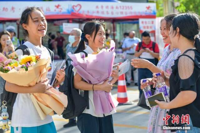 资料图：6月10日，海南省海口市海南中学考点外，家长为刚刚走出考场的考生送上鲜花。当日，海南省2021年高考结束。中新社记者骆云飞摄