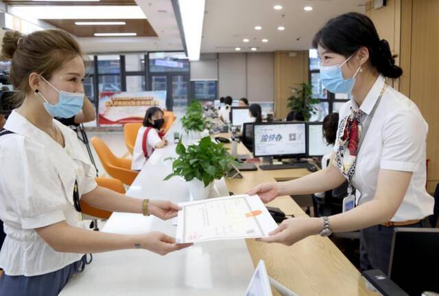 姚女士在重庆高新区领取了全国首张整合卫生许可信息的“一码通行”营业执照雷键摄