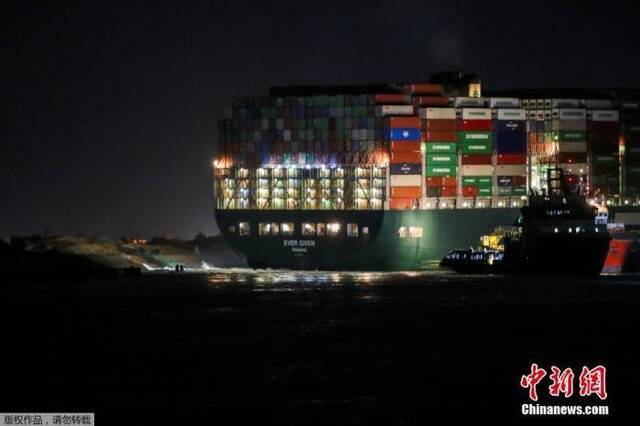 资料图：当地时间3月27日，埃及苏伊士运河，搁浅的集装箱船“长赐号”在深夜灯火通明。