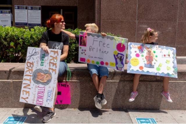 （图说：6月23日，洛杉矶法院门口，布兰妮的支持者带着孩子们举着“解放布兰妮”的标语。图/The New York Times）