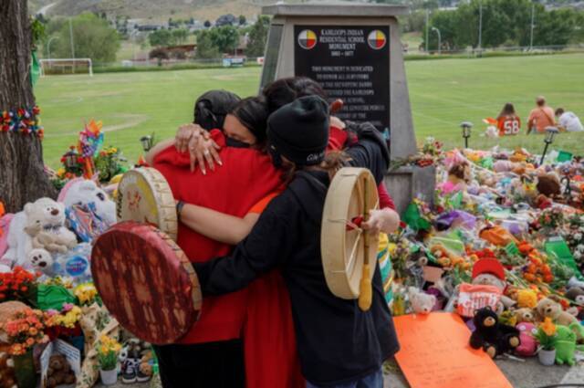 （图说：坎卢普斯学校旧址纪念碑前，前来悼念的民众在拥抱。图/AFP）