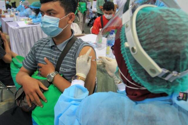 6月14日，一名男子在印度尼西亚日惹接种新冠疫苗。（新华社）