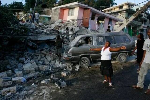  2010年1月13日，在发生地震的海地首都太子港，一名女子在被震毁的房屋旁哭泣。新华社/路透
