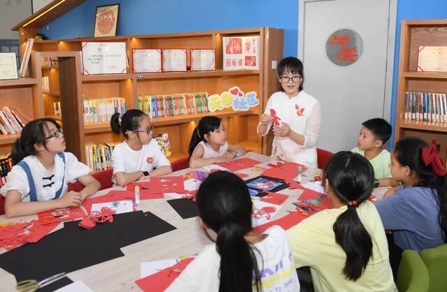 7月7日，浙江在安吉昌硕街道天目社区幸福邻里中心，志愿者给辖区青少年上剪纸课。暑假期间，浙江安吉在多个乡镇街道共开放儿童之家等场所作为“暑期乐园”，丰富孩子们的暑期生活。新华社记者翁忻旸摄影