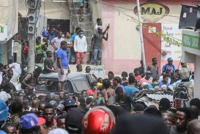 2021年7月8日，海地太子港，警察押送被指控参与刺杀总统的嫌疑人，民众围观。图片来源：视觉中国