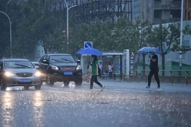 ▲7月11日，暴雨中的行人。新京报记者陶冉摄