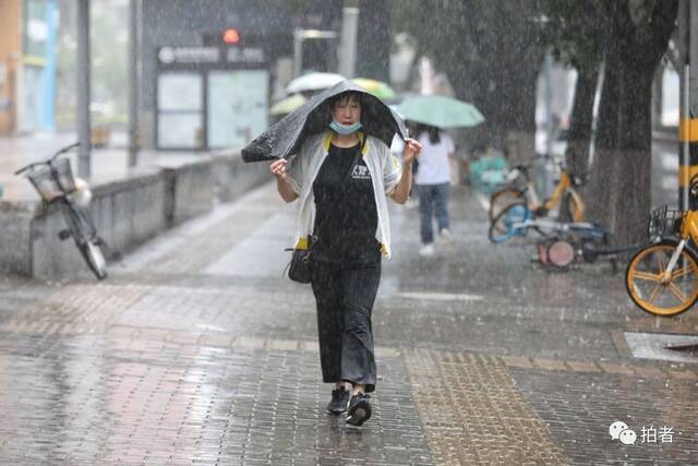 7月12日，蒲黄榆，市民用塑料袋遮雨出行。摄影/新京报记者王嘉宁