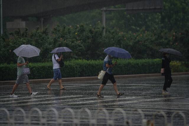 在北京市亦庄桥地铁站附近，市民在雨中出行。