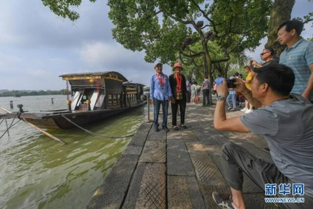 7月1日，两名老党员在浙江嘉兴南湖湖心岛停泊的南湖红船旁拍照留影。新华社记者徐昱摄