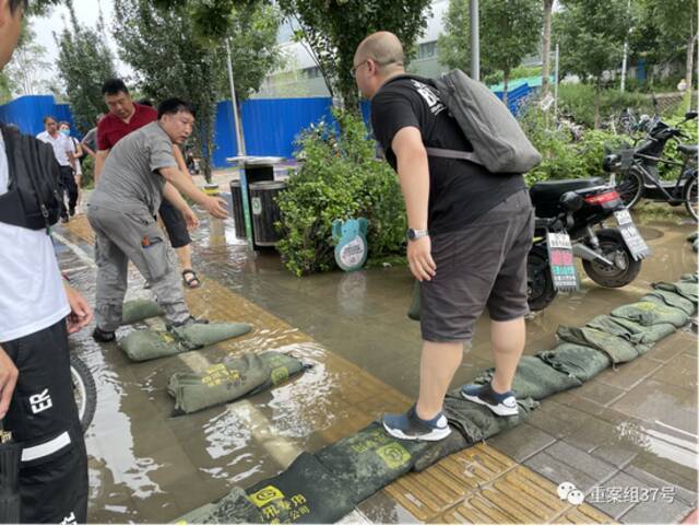 ▲金安桥地铁站C口，工作人员铺设防洪沙袋，供行人通过。新京报记者左琳摄