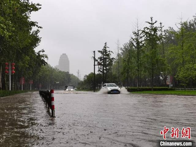 图为7月20日上午，郑州市区，汽车在积水的道路行驶。李贵刚摄