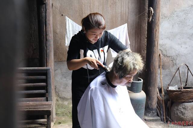 灵川县纪委监委干部小龙正在给赵奶奶的儿子理发。