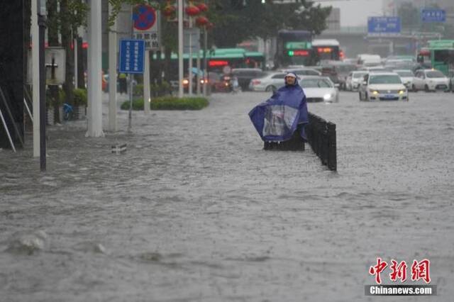 7月20日，河南郑州，市民冒着暴雨出行。近日，郑州连遭暴雨袭击，持续强降雨导致部分街道积水严重。中新社记者李超庆摄