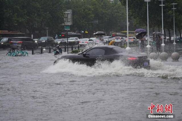 7月20日，河南郑州，车辆经过积水路段。近日，郑州连遭暴雨袭击，持续强降雨导致部分街道积水严重。中新社记者阚力摄