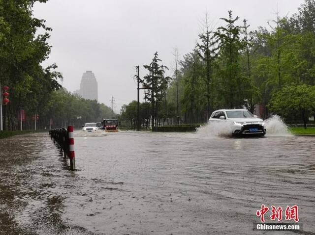  7月20日，河南郑州，车辆从积水路段通过。近日，郑州连遭暴雨袭击，持续强降雨导致部分街头积水严重。中新社记者李贵刚摄