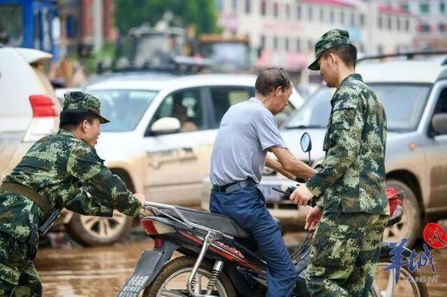武警官兵帮助群众将车辆推出淤泥（图源：羊城晚报）