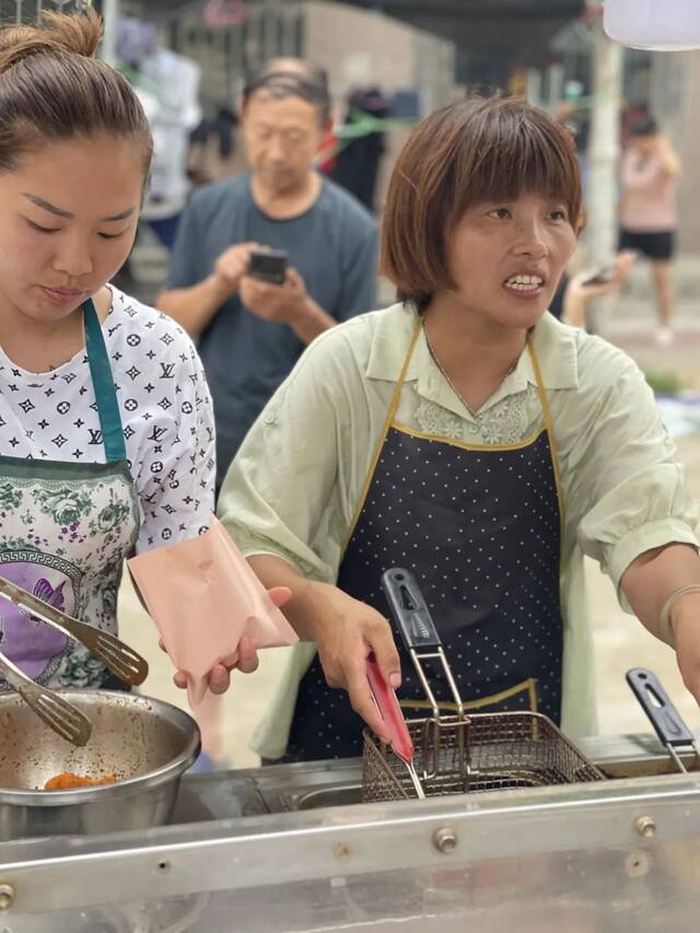 7月22日下午，米河镇放晴，下午5点钟，小吃车纷纷出摊，卖炸鸡的姐妹俩一个炸，一个拌料，忙得不可开交，短短一个小时，就收摊了。新京报记者王瑞文摄