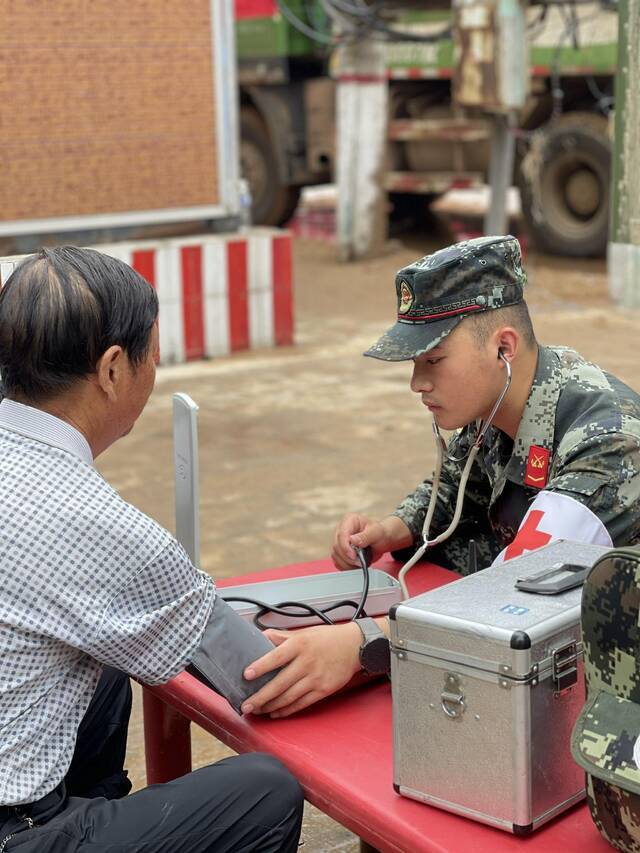 武警第一机动总队设立的医疗点，7月23日，一名军医正在给居民量血压。新京报记者王瑞文摄