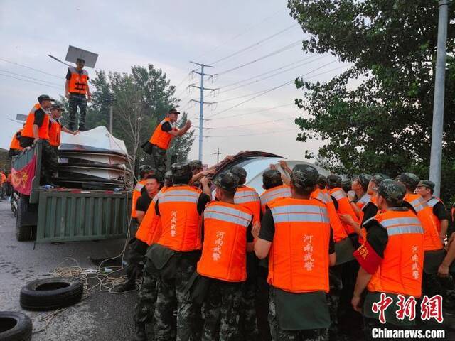 图为武警河南总队机动支队官兵正把船放入水中，准备乘船去堤坝处。杨大勇摄