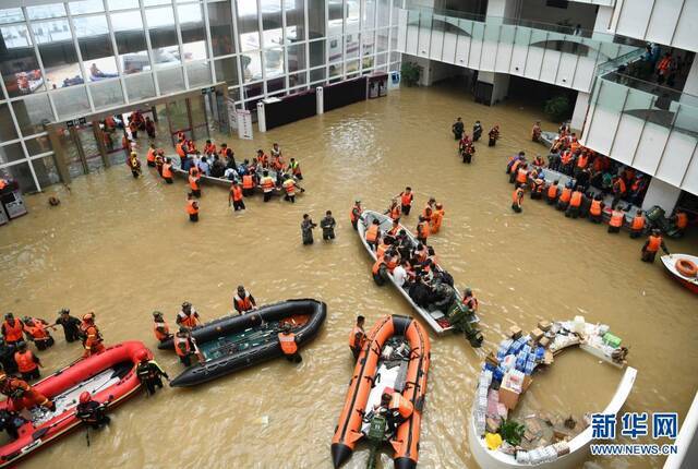 这是在阜外华中心血管病医院门诊部，救援人员在积水的大厅内驾驶舟艇转移病患。