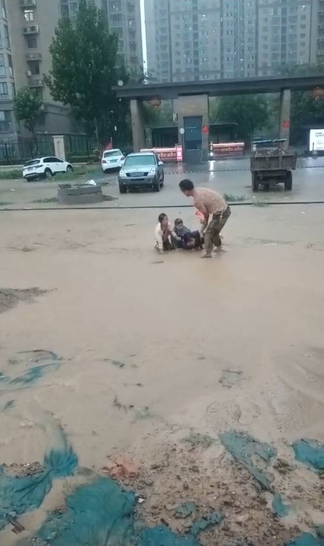  7月20日，王西超将掉进水坑的一家三口拉了出来。来源：视频截图