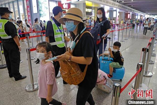 资料图：旅客带着孩子在铁路上海虹桥站出示健康码。殷立勤摄