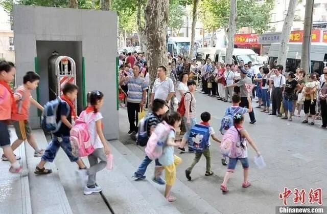 资料图：武汉一小学门外等待学生放学的家长们。中新社发张畅摄