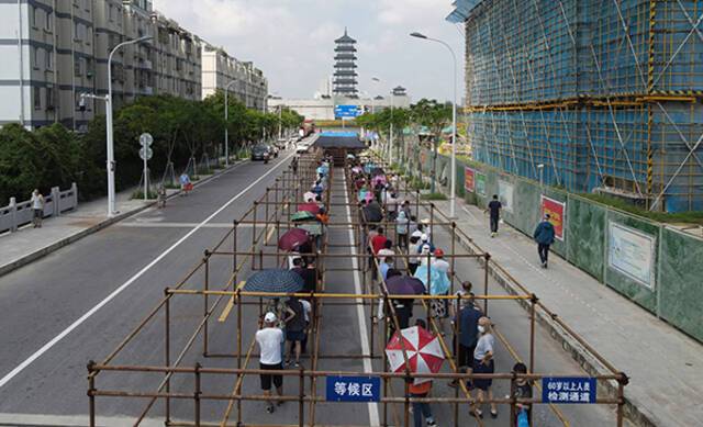 2021年8月7日，市民在江苏省扬州市广陵区汤汪乡杉湾花园社区核酸检测点排队等候核酸检测取样。人民视觉图