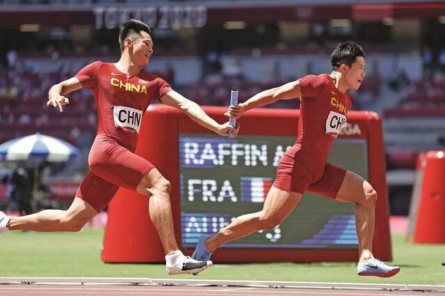 ·2021年8月5日，东京奥运会男子4×100米接力第一轮比赛中，谢震业和苏炳添（右）在比赛中交接棒。