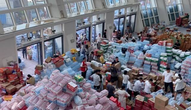 河南新乡接收捐赠物资的临时仓库，物资堆积如山。图/视频截图