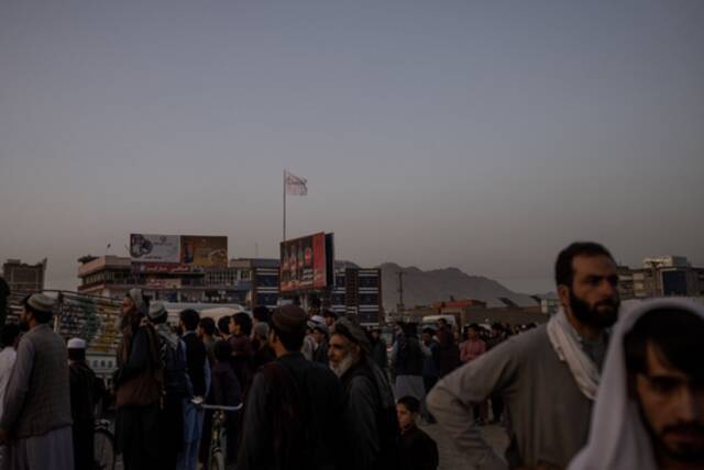 （图说：15日，塔利班进入喀布尔后，将组织的旗帜插在了城内一块可口可乐广告牌上。图/ The New York Times）
