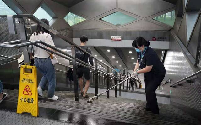 工作人员清理进站口台阶上的雨水。京港地铁供图